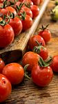 Cherry Tomatoes On Display On Wooden Chopping Board And Wooden Table Stock Photo