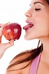 Closeup Of Young Girl Tasting The Apple By Her Tounge Stock Photo