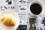 Croissant And Black Coffee On Newspaper Background Stock Photo
