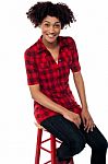 Curly Haired Fashion Model Sitting On Red Stool Stock Photo