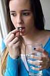 Depressed Young Woman Taking Pills At Home Stock Photo