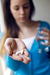 Depressed Young Woman Taking Pills At Home Stock Photo