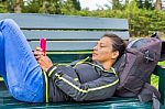 Dutch Woman Operating Mobile Phone Lying On Bench Stock Photo