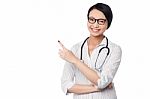 Female Physician Pointing And Looking Away Stock Photo