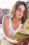 Girl Reading Book Outdoors Stock Photo