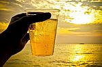 Glass Of Beer On Beach Sand At Sunset Stock Photo