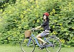 Happy Smiling Girl Riding A Bicycle In The Park Stock Photo