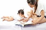 Mother Is Reading A Book For Her Baby Stock Photo