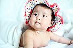 Newborn Baby With Colorful Floppy Hat Lying Down On A White Blan Stock Photo