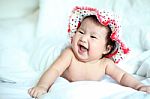 Newborn Baby With Colorful Floppy Hat Lying Down On A White Blan Stock Photo