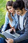 Portrait Of Young Couple At The Park Using A Laptop Stock Photo
