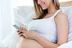 Pregnant Woman Using Her Mobile Phone On Sofa Stock Photo