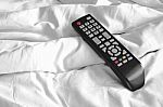 Remote On Bed Sheets Stock Photo