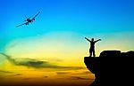 Silhouette Of A Man On The Rock And Silhouette Commercial Plane Stock Photo