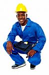 Smiling African Worker Squatting Stock Photo