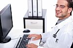 Smiling Young Doctor Working On His Desk Stock Photo
