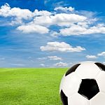 Soccer Ball With Green Grass Field Against Blue Sky Stock Photo