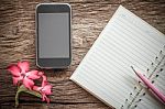Surface Of A Wooden Table With Notebook, Smartphone, Desert Rose Stock Photo
