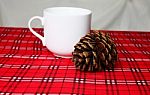 Warm Drink, White Mug And Pine Cone On Red Table Cloth (front Fo Stock Photo