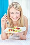 Woman Eating Salad In Bed Stock Photo