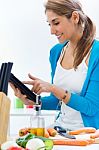 Woman In Kitchen Looking For A Recipe On The Internet Stock Photo