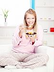 Woman On Sofa Eating Cake At Home Stock Photo