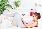 Woman With Laptop Lying On Sofa Stock Photo