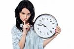 Young Brunette With Wall Clock Gesturing Silence Stock Photo