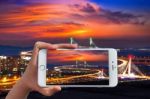 Hand Holding Smart Phone Take A Photo At Incheon Bridge With Sunset Stock Photo