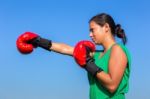 Young Woman Wearing Red Boxing Gloves With Blue Sky Stock Photo