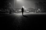 Girl Walking In An Urban Street At Night Under Streetlights Stock Photo