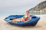 Woman Lying In Rowing Boat On Greek Beach Stock Photo