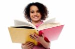 Adorable School Girl Reading A Book With A Smile Stock Photo