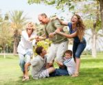 Family Holding Back Grandfather And Having Fun Stock Photo