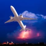 Commercial Airplane Flying With Clouds And Thunderstorm Backgrou Stock Photo