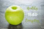 Green Apple On The Table With Healthy Quote Stock Photo