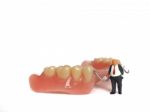 Miniature Elderly Standing On Removable Denture, On White Background. Dental Health Concept Stock Photo