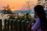Happy Young Woman Standing Watching The Sunset Over The Lake Stock Photo