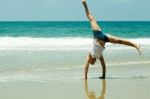 Girl Doing cartwheel At Beach Stock Photo