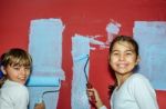 Eight Year Old Twins Girls Painting The Wall At Home Stock Photo