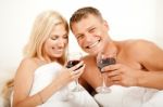 Couple Lying In Bed Sharing Wine Stock Photo