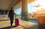 Traveling Woman And Luggage Walking In Airport Terminal And Air Plane Flying Outside Stock Photo