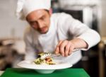 A Chef Arranging Tossed Salad In A White Bowl Stock Photo