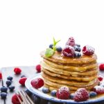Pancakes With Honey And Berries On White Background Stock Photo