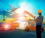 Working Man In Logistic Business Working In Container Shipping Yard With Dusky Sky And Jet Plane Cargo Flying Above Use For Land To Air Transport And Freight Stock Photo