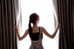 Young Woman Opening Curtains Stock Photo