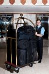 Standing Bellboy With Luggage Cart Stock Photo
