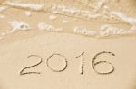 2016 Inscription Written In The Wet Yellow Beach Sand Being Wash Stock Photo
