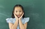 Little Asian Girl With Hands Close To Face Smiling Looking At Camera Stock Photo