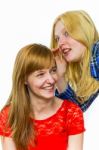 Blonde Girl Whispering In Ear Of Redhead Girlfriend Stock Photo